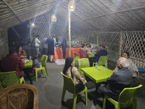 a group of people sitting at tables in a restaurant at The Ashok Vatika Farms and Stay in Haridwār