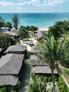 an aerial view of a resort with thatched roofs and the ocean at The Lazy Lodge in Ko Lanta