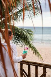 a woman holding a drink on the beach at The Lazy Lodge in Ko Lanta