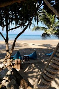 a hammock on a beach with a palm tree and the ocean at The Lazy Lodge in Ko Lanta