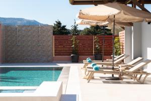 a pool with two lounge chairs and an umbrella at Elias' Rest Villa in Pastida