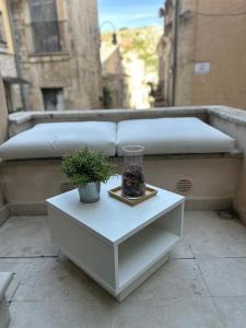 a white table with a vase on it on a balcony at CasaCastellett in Modica
