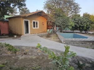 a small house with a swimming pool in a yard at The Ashok Vatika Farms and Stay in Haridwār
