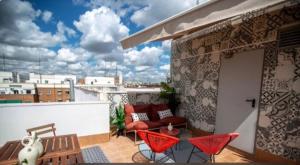 eine Terrasse mit roten Stühlen und einem Sofa auf dem Balkon in der Unterkunft Apartamento 7 Atocha Delicias Madrid Rio in Madrid