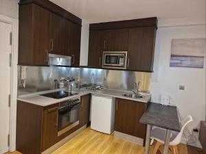 eine Küche mit braunen Schränken und einer Spüle und einer Mikrowelle in der Unterkunft Apartamento 7 Atocha Delicias Madrid Rio in Madrid