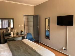 a bedroom with a bed and a television on the wall at The Wild Peach - Menlyn in Pretoria