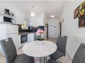 a kitchen with a white table with chairs and a vase of flowers at Apartment Tafra 1 in Lokva Rogoznica