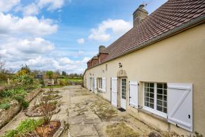 a white building with white doors and a yard at La Maison de Lallier - à 35 min de Cherbourg in Turqueville