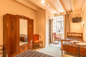a bedroom with a cabinet and a bed and a tv at Auberge le John Steele in Sainte-Mère-Église