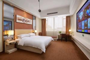 广州Junyue Airport Hotel -Free Shuttle Bus Guangzhou Baiyun airport& C-harge shuttle bus for the Canton fair from April 15-May 5的一间配有一张大床和一台平板电视的卧室