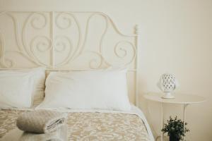 a white bed with a white headboard and a table at Dimora Del Vicolo in Ostuni +20 photos