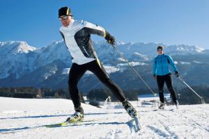 バート・ミッテルンドルフにあるFamilien Zeitの雪に覆われた坂道を2人がスキーで下りている