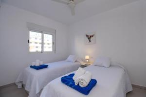 two beds in a white room with a window at Strandapartment Sunnybeach Dénia in Denia