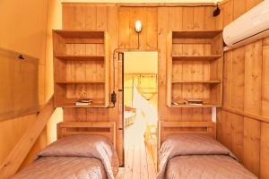 two beds in a room with wooden walls at Calasole Glamping in Pescia Romana +85 photos