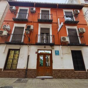 an orange and white building with a door and balconies at Barbieri Granada Pensión in Granada