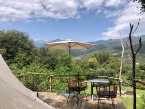 a table and chairs on a deck with an umbrella at glamping Bonheur in Arles-sur-Tech +5 photos