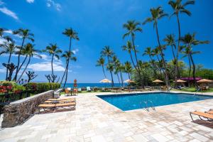a resort pool with palm trees and the ocean at Elua 406 in Wailea