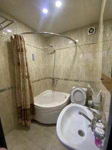 a bathroom with a sink and a toilet and a tub at Lotus Hotel in Yakkasaray