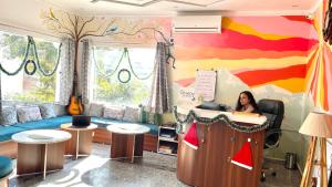 a woman sitting at a desk in a room with a colorful wall at GreenDay Escapes Rishikesh in Rishīkesh