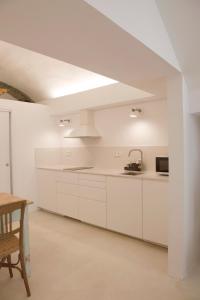 Una cocina blanca con gabinetes blancos y una mesa. en Maram Brava casa centro Begur Metge Pi, en Begur