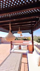 a patio with a bed and two chairs under a pergola at Villa Belle vue - with a private & Heated pool in Marrakesh