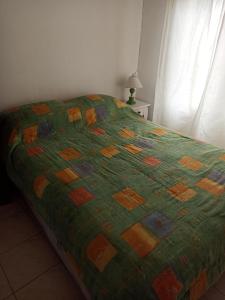 a bed with a green quilt on it in a bedroom at Chalet Faro in Mar del Plata