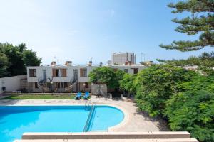 a swimming pool in front of a house at Apto JACARANDA LAS AMERICAS in Playa de las Americas