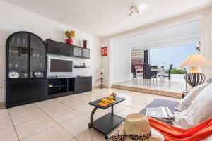 a living room with a couch and a tv at Apto JACARANDA LAS AMERICAS in Playa de las Americas