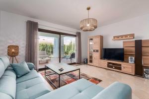a living room with a blue couch and a tv at Albatros in Casares