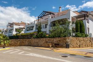 a building behind a stone wall and a street at Albatros in Casares