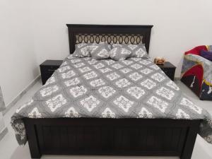 a bed with a black and white comforter and pillows at Rama Rooms in Abu Dhabi