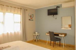 a bedroom with a desk and a television on the wall at Imvomvo Country Lodge and Conference Center in Mount Ayliff