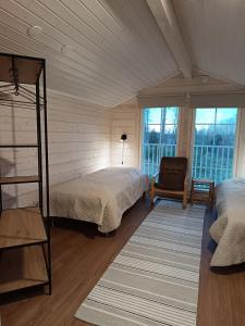 a bedroom with two beds and a chair and windows at Mäkelän Lomatuvat Bed and Breakfast in Hyytiälä