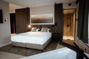 a bedroom with a white bed and a bath tub at Anatura Luxembourg in Weiswampach