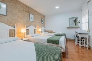 a hotel room with three beds and a desk at El Nogal Home in Málaga