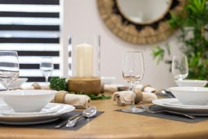 a wooden table with plates and glasses on it at Watford 2-Bed Oasis - 20-min to London - Central in Watford
