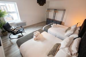 ein Zimmer mit zwei Betten und einem Stuhl mit einer Kamera in der Unterkunft Stylist 2-Bedroom Flat - Watford Central in Watford