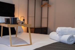 a bed with a small table with towels on it at Watford 2-Bed Oasis - 20-min to London - Central in Watford