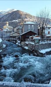 a river with snow on the ground next to buildings at Appartamento Antony in Temù
