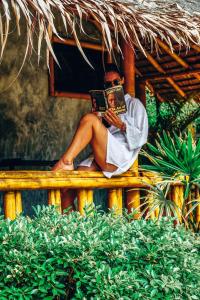 a man sitting on a fence reading a book at The Lazy Lodge in Ko Lanta