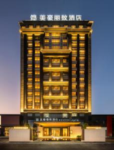 广州Mehood Lestie International Hotel Panyu Flagship Branch - Free Shuttle Bus to Canton Fair Complex During Canton Fair Period & Free Breakfast & Free Afternoon Tea & Free Midnight Snack的一座有灯的建筑,上面有标志