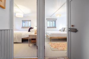 a room with two beds and a door leading to a bedroom at Mill End by Big Skies Cottages in Weybourne
