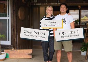 a man and a woman holding up signs at Guesthouse Mikansei in Kawanehon