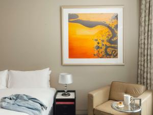 a bedroom with a bed and a chair and a painting at The Olsen Melbourne Art Series in Melbourne