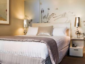 a bedroom with a large white bed with two lamps at The Olsen Melbourne Art Series in Melbourne