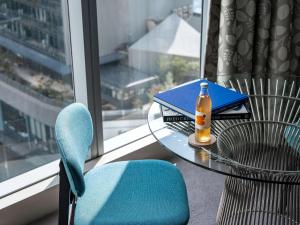 a table with a bottle and a book and a chair at The Olsen Melbourne Art Series in Melbourne