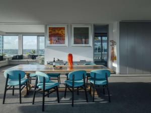 a living room with a wooden table and blue chairs at The Olsen Melbourne Art Series in Melbourne