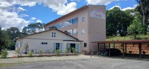 a pink and white building with a parking lot at Hotel Rafael in São Bento do Sul