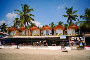 a hotel on the beach with palm trees in the background at Sameer beachfront Cottages in Canacona