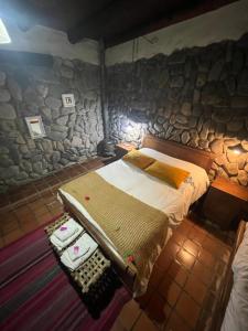 a bedroom with a bed and a stone wall at Rincon del Valle in San Salvador de Jujuy